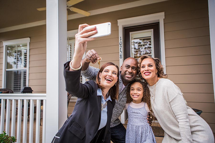 Agent taking a group photo of family who has just closed on a home purchase.
