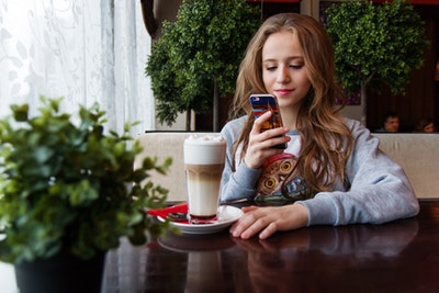 woman taking smartphone photo of coffee drink