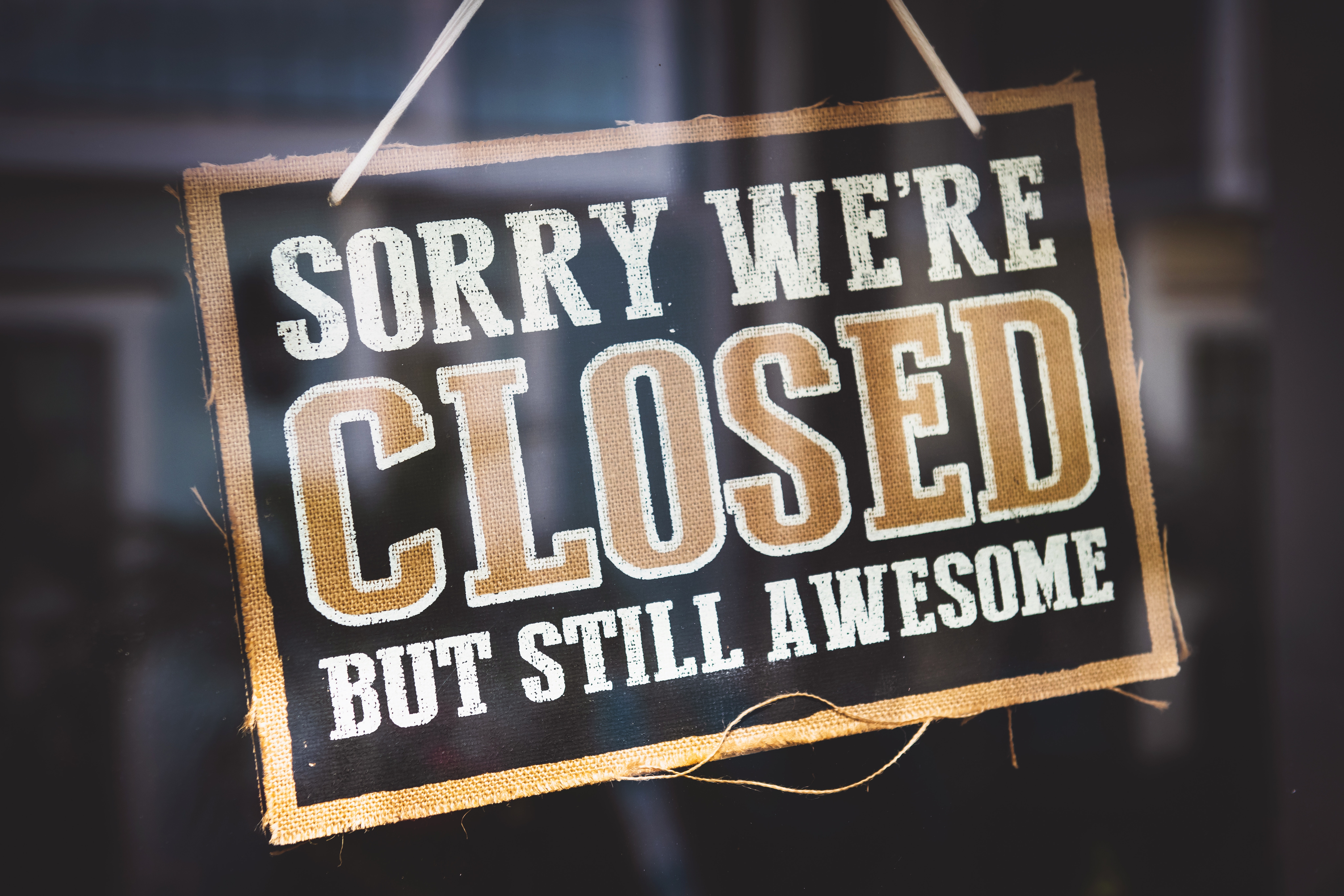 sorry we're closed sign hanging on glass window