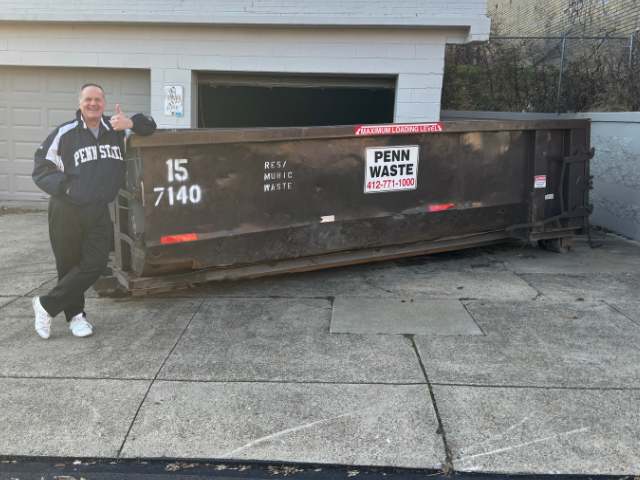 man standing near dumpster near two car garage