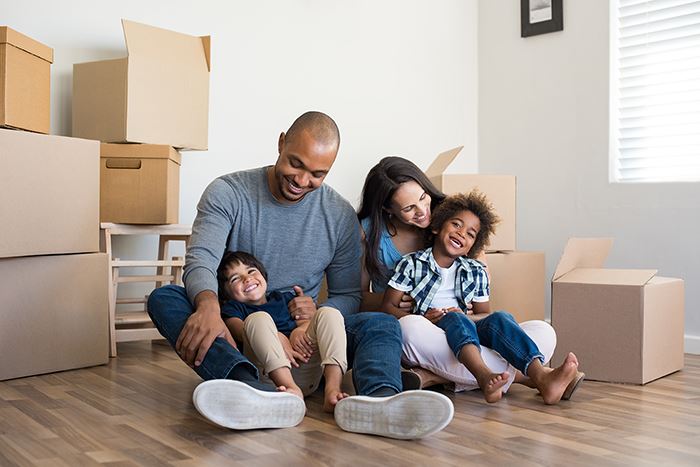 family sitting on the floor with boxes in new home