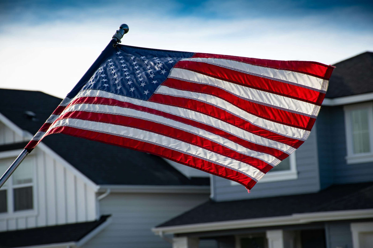 american flag waving with houses in the background