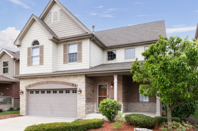 beige suburban house with landscaping in front