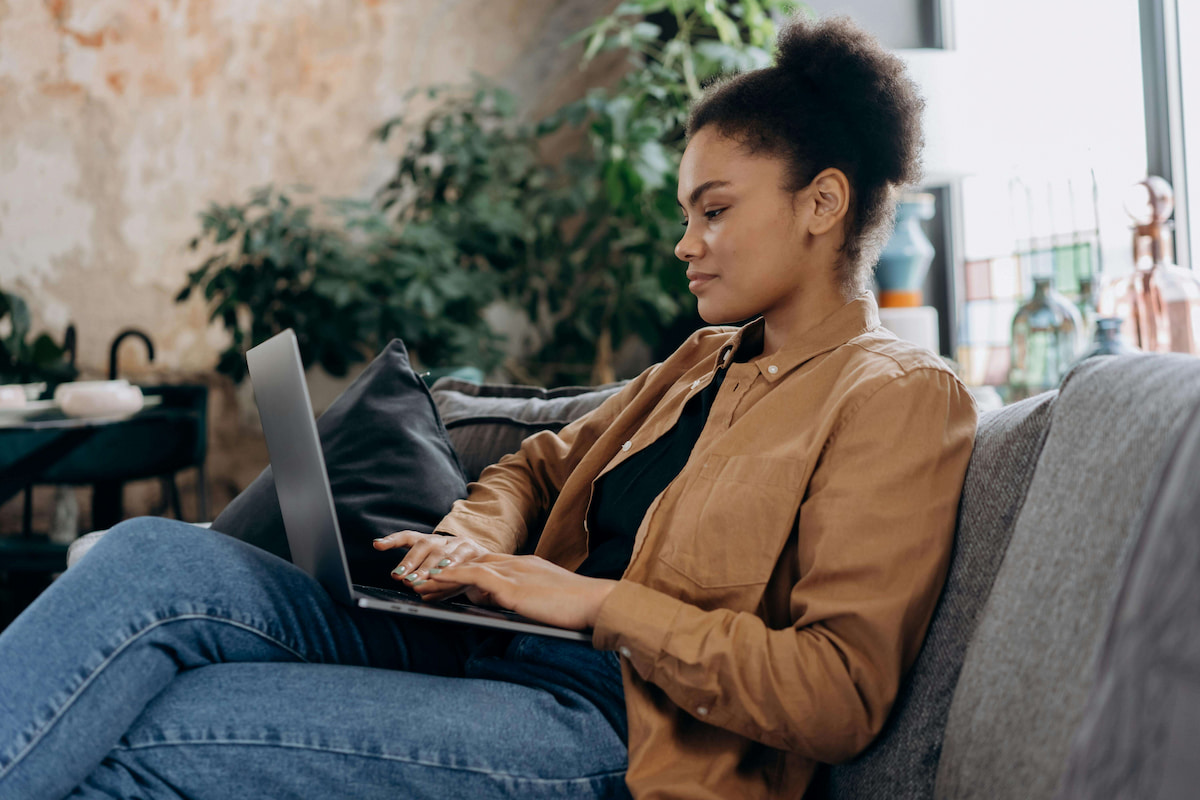 woman using laptop on a couch at a coffee shop