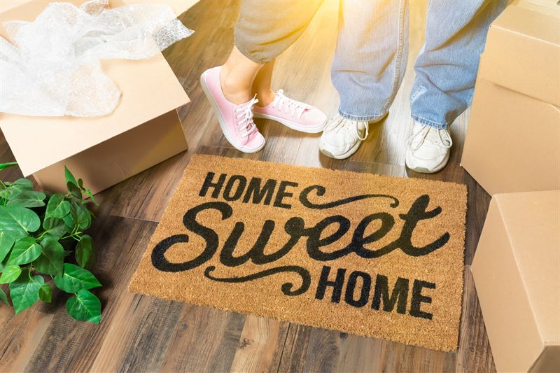 couple standing on a home sweet home doormat