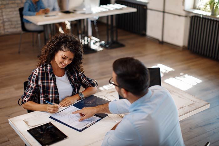 man helping a woman with paperwork in an office setting