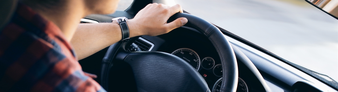 looking over the shoulder of a man holding the wheel of a vehicle