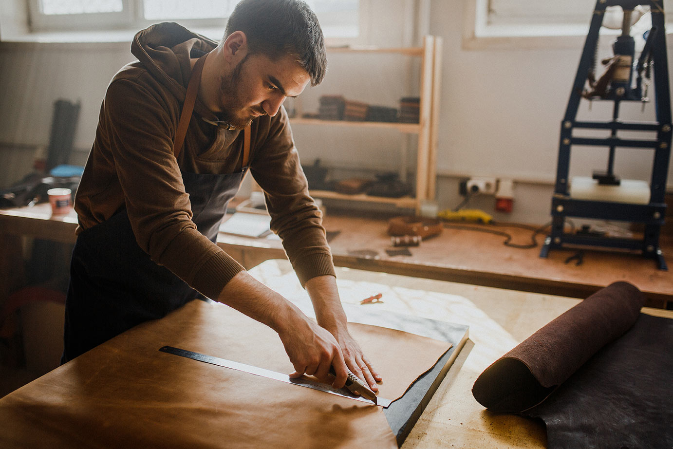 Man in a workshop cutting a piece of material